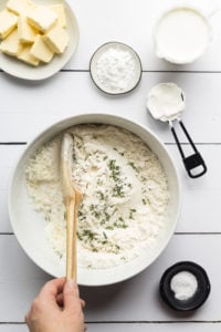 Southern Biscuits Recipe ingredients in a bowl stirred with a wooden spoon