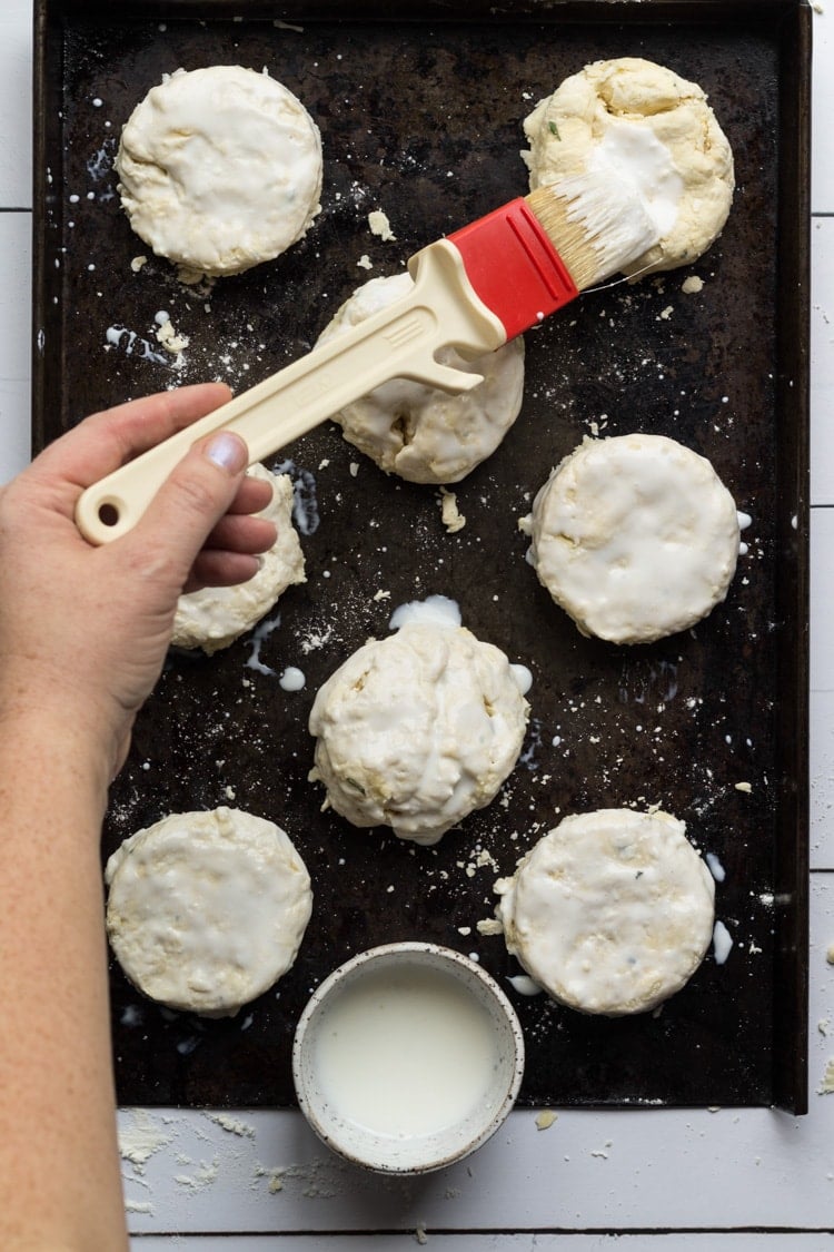 Brushing southern biscuit dough with buttermilk on a sheet pan