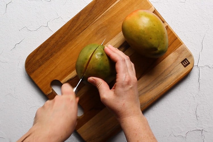 Slicing mango on a wooden cutting board