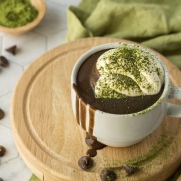 Matcha Hot Chocolate Recipe up close with whipped cream on a wooden board