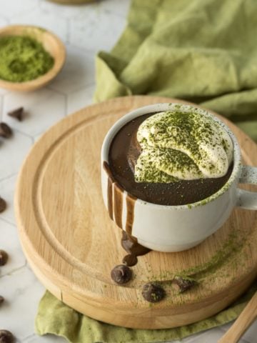 Matcha Hot Chocolate Recipe up close with whipped cream on a wooden board