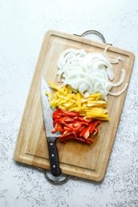 Chopped bell peppers and onion on a chopping board for fajita bowls