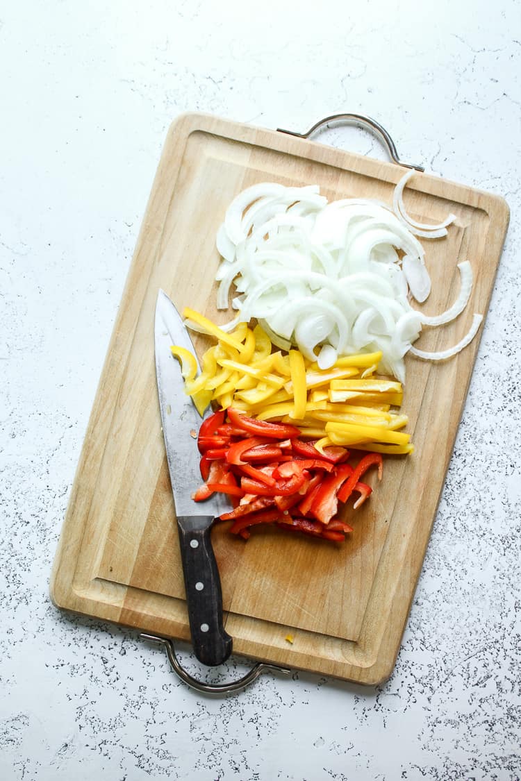 Chopped bell peppers and onion on a chopping board for fajita bowls