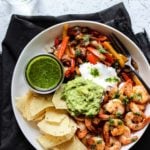 Shrimp Fajita bowls with green chile chimichurri sauce and limes on a plate