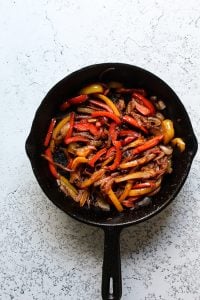 Sauteed fajita vegetables in a cast iron skillet for fajita bowls