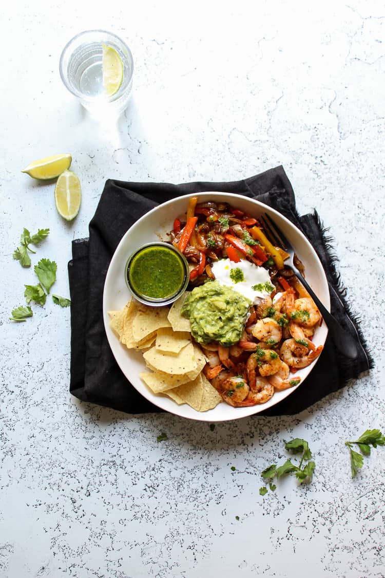 Shrimp fajita bowls on a plate with guacamole and sour cream