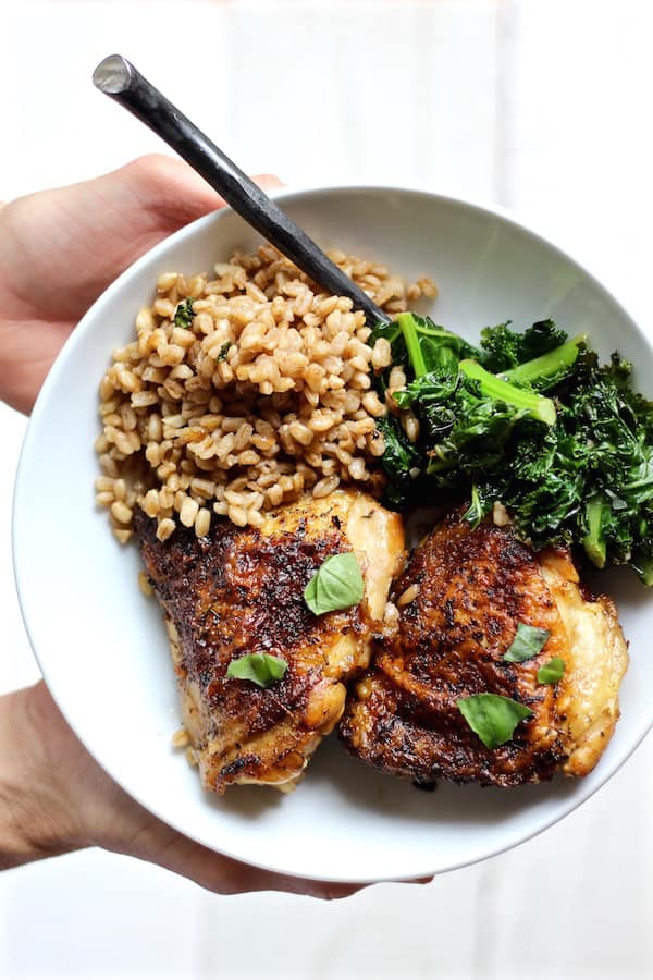 crispy chicken kale farro salad plated with hands