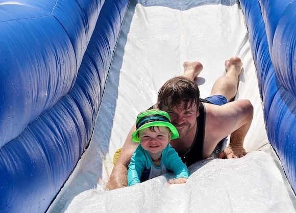 Dad and son sliding down water slide together