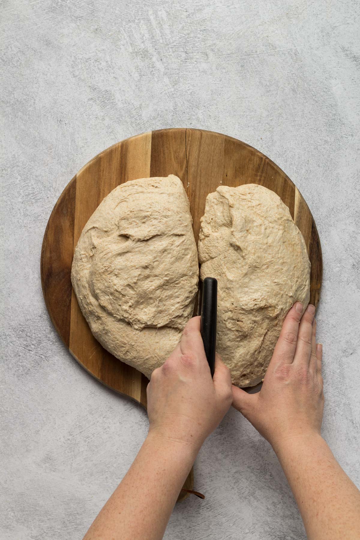 Cutting bread dough in half with a bench scraper