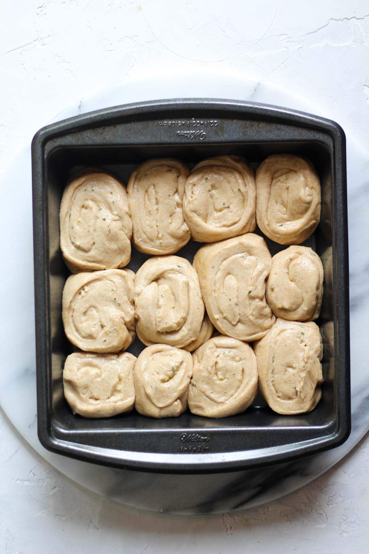 Sourdough garlic rosemary rolls proofed in a pan