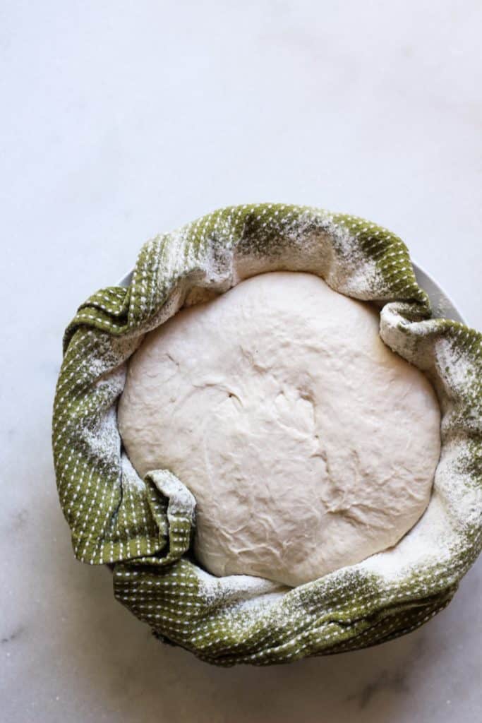 Sourdough Bread fermenting in a salad bowl with a kitchen towel