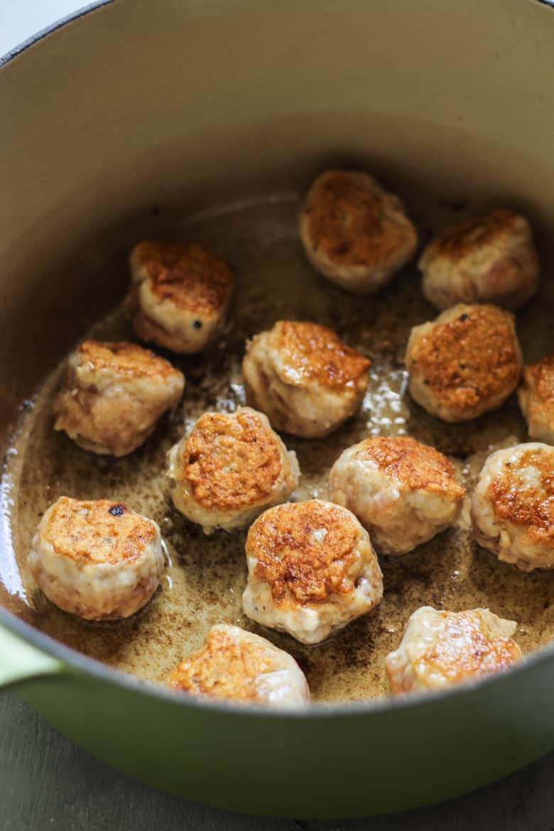 Chicken meatballs sauteeing in a dutch oven for chicken meatball soup
