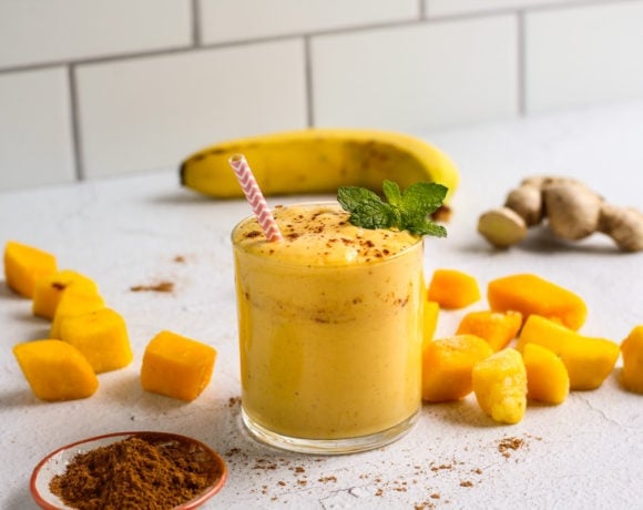 Mango Lassi Smoothie in a glass with mango slices and a banana