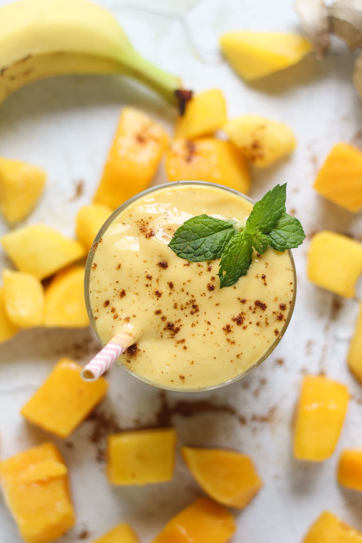 Mango lassi smoothie with mint and fresh mango in a cup