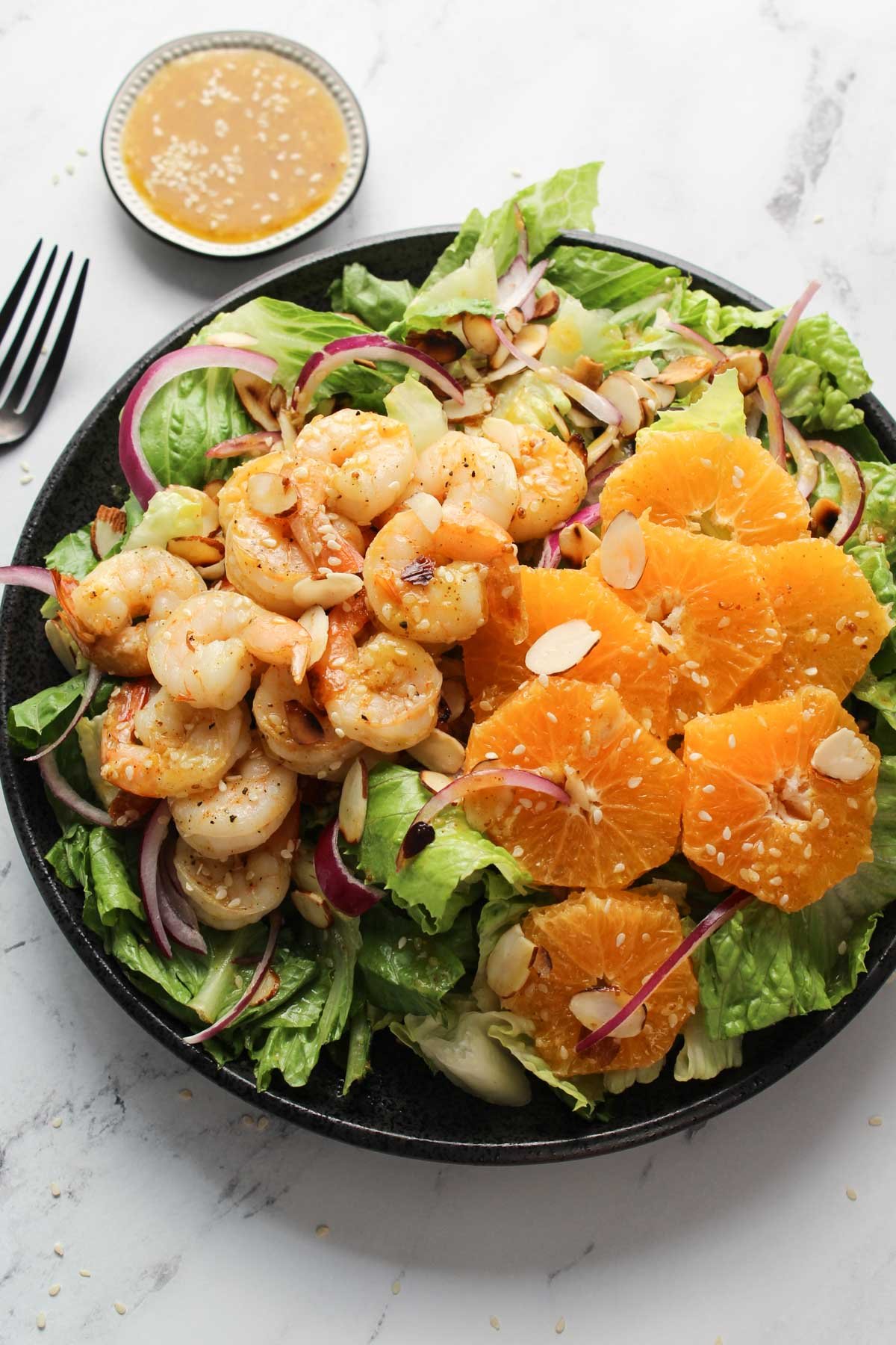 Shrimp Salad on a plate with orange sesame dressing in a bowl