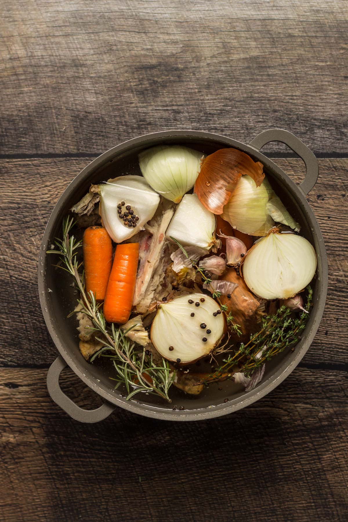 Carrots, onions, garlic, and chicken bones in a pot