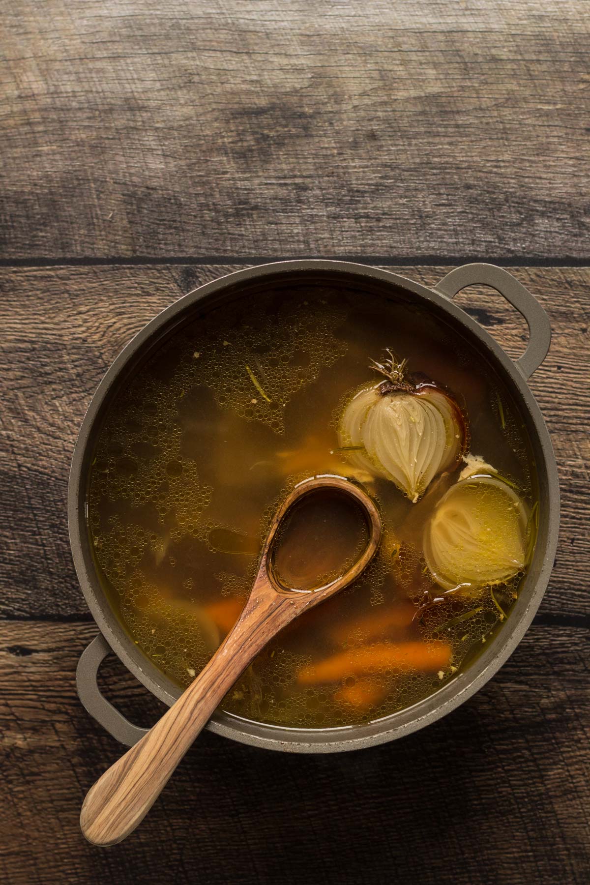 Chicken stock in a pot with a wooden ladle