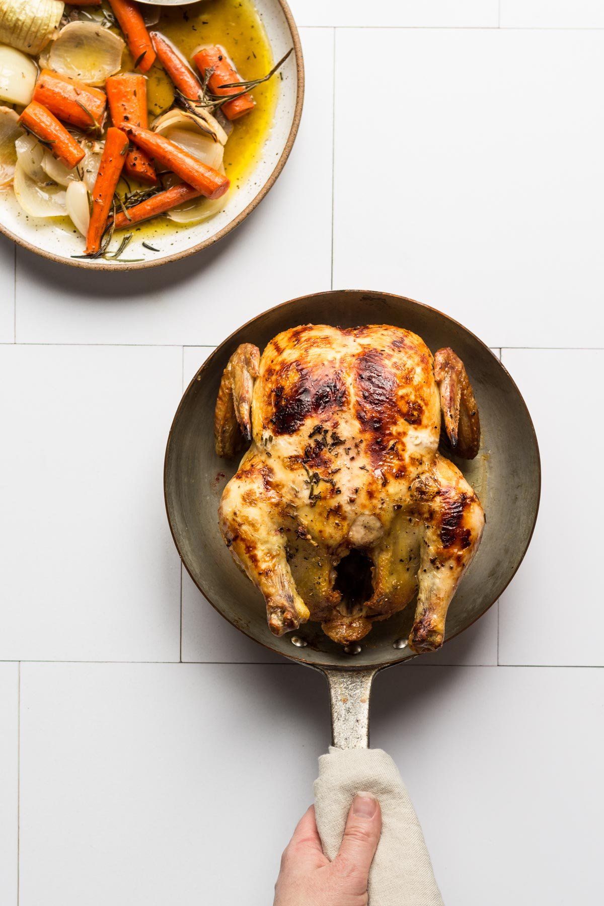 A whole chicken with vegetables in a pan