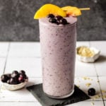 Blueberry smoothie in a glass with peaches on top