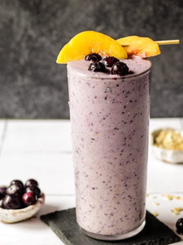 Blueberry Peach Oatmeal smoothie in a glass with peaches on top
