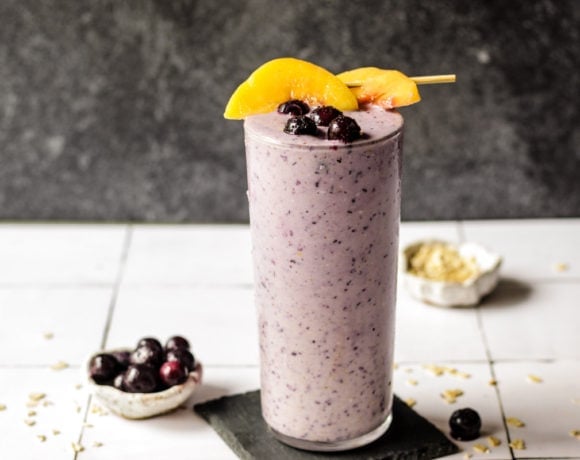 Blueberry Peach Oatmeal smoothie in a glass with peaches on top