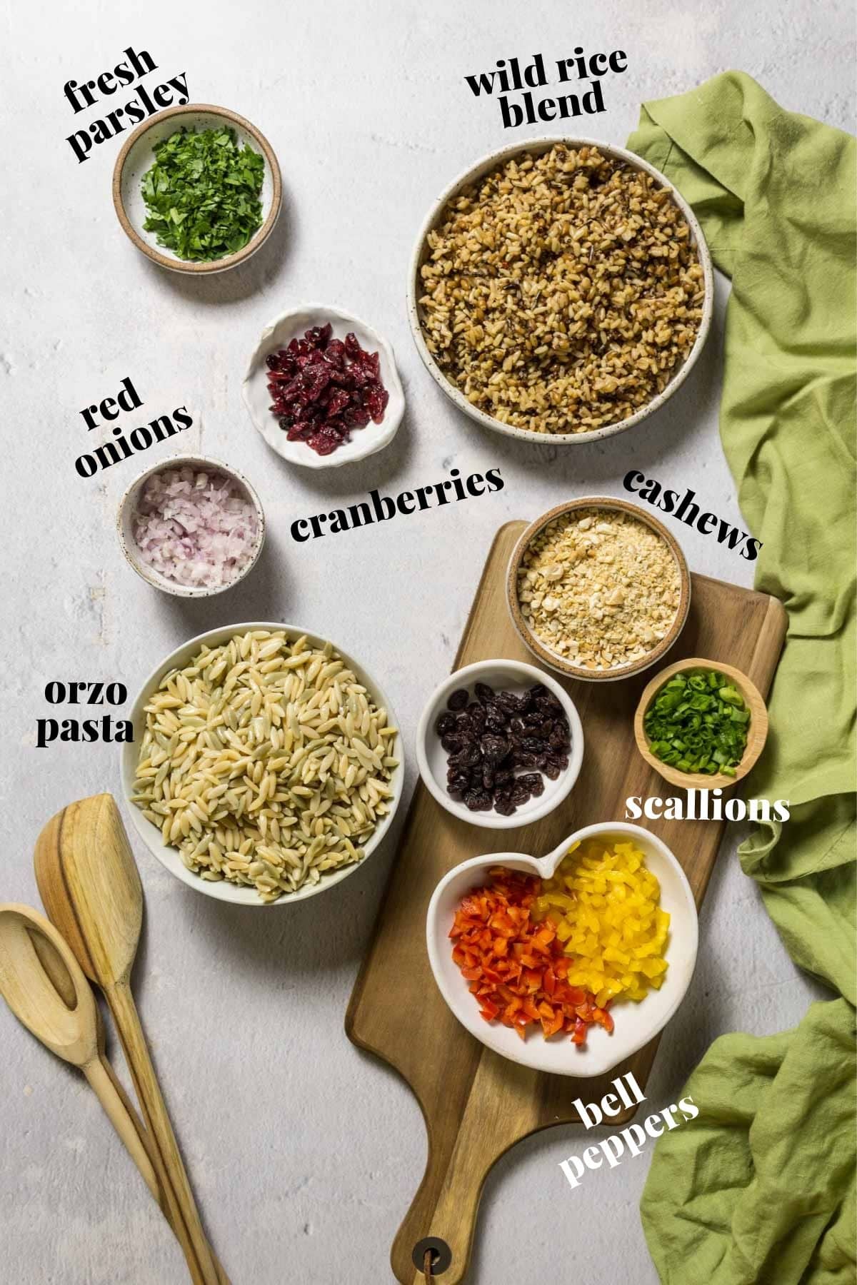 Bell peppers, rice, orzo, and onions in bowls on a wooden board