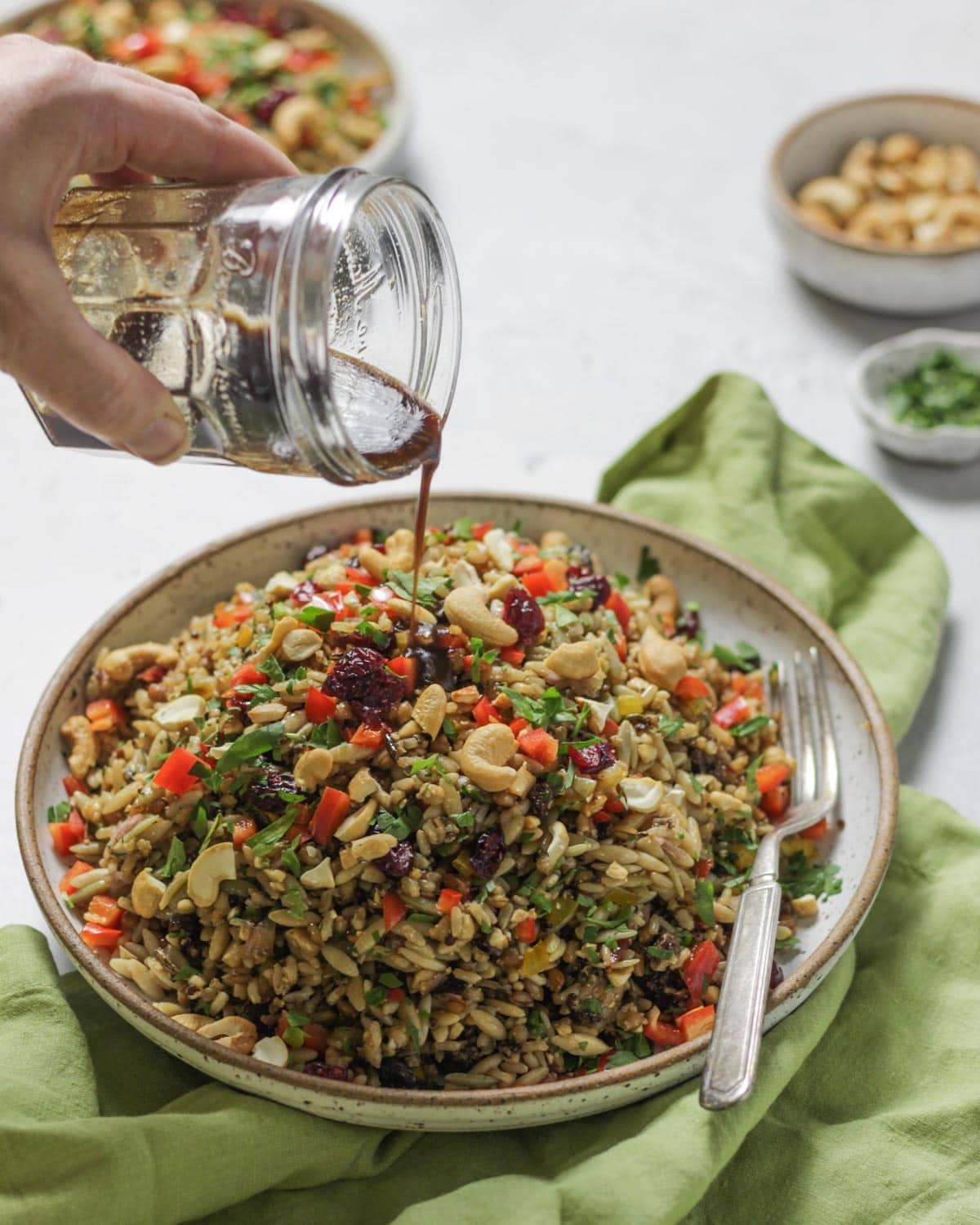 Pouring vinaigrette over an orzo wild rice salad