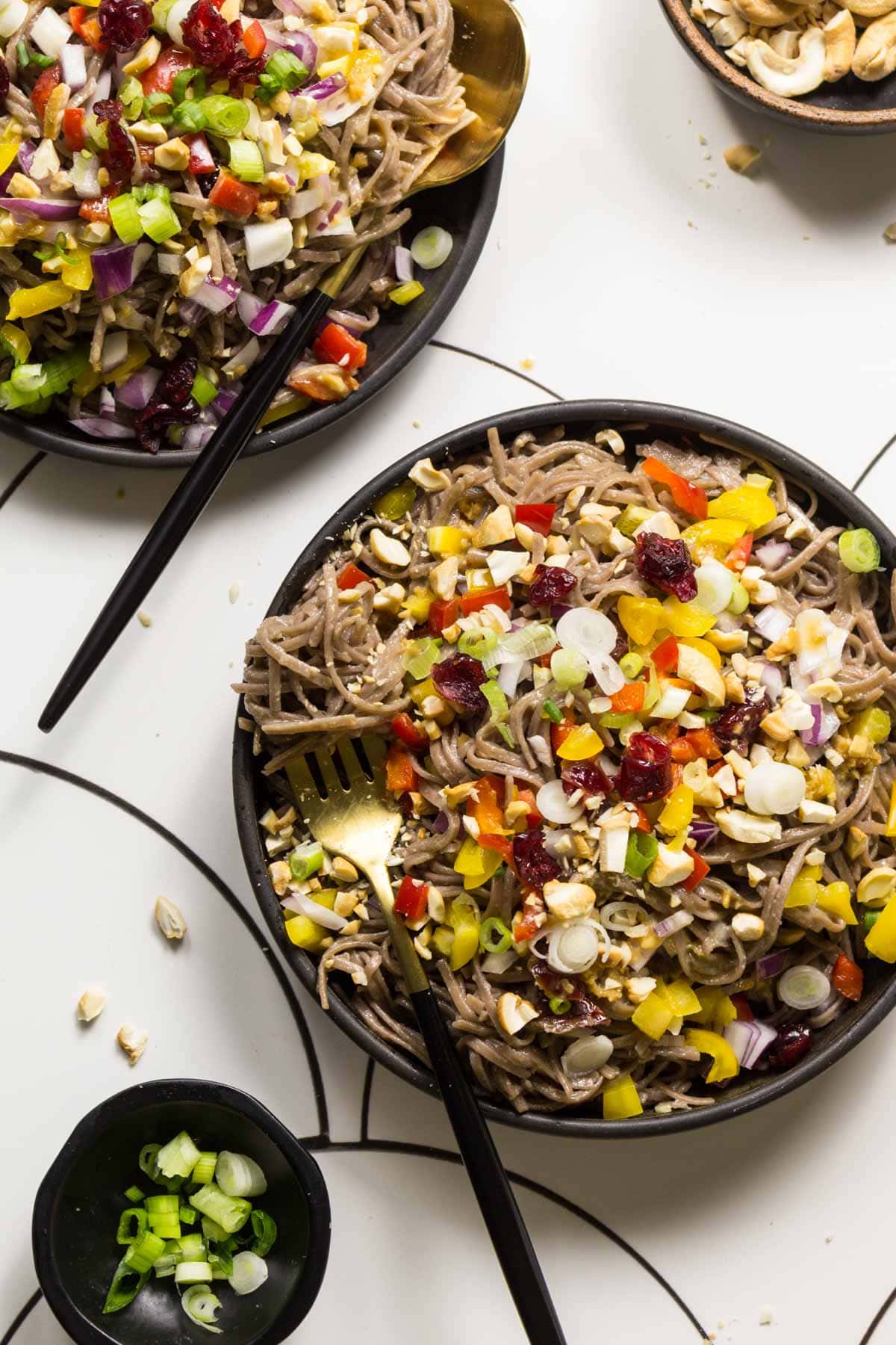 Soba noodle salad topped with veggies on plates