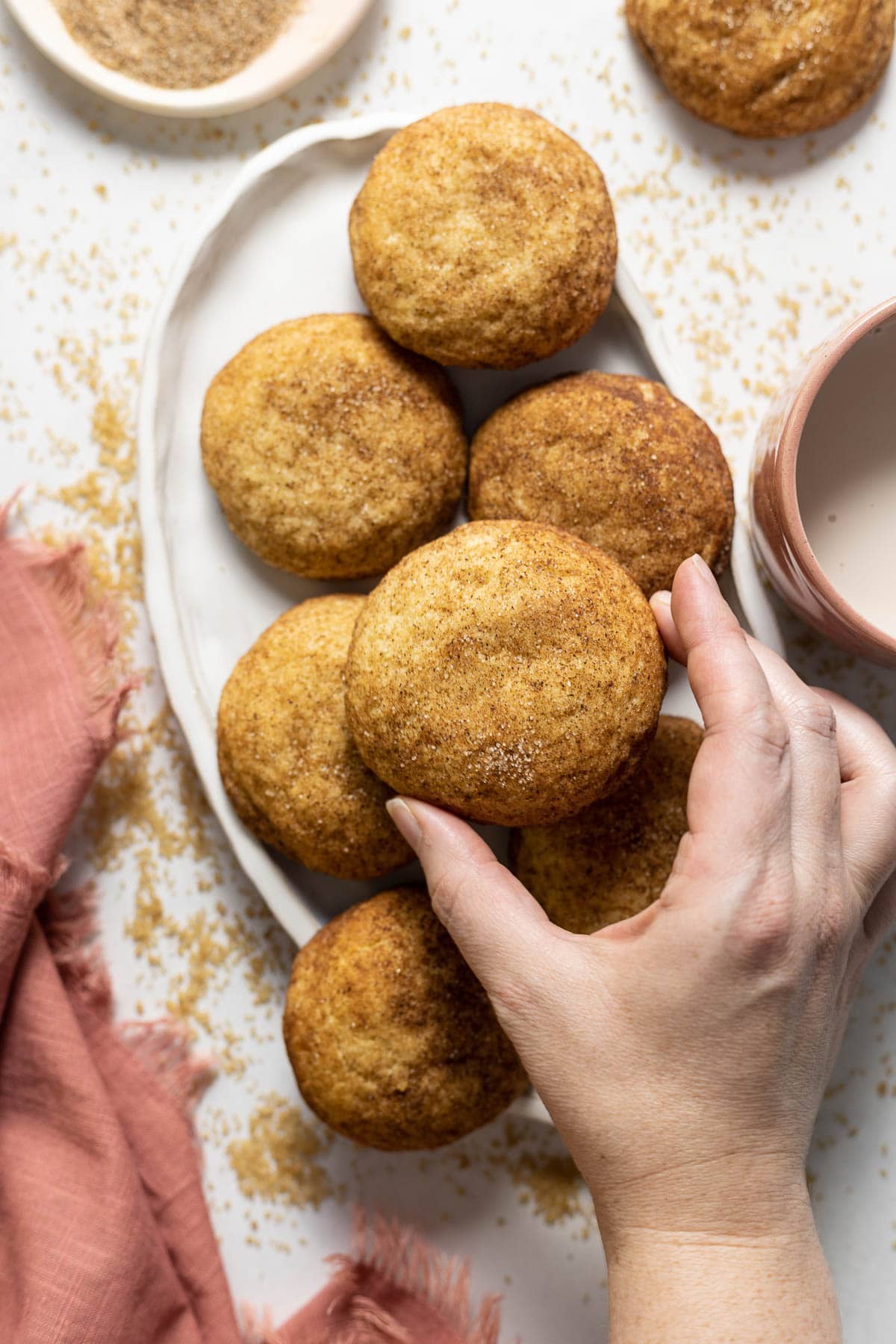 Chai snickerdoodle cookies held in a hand on a plate