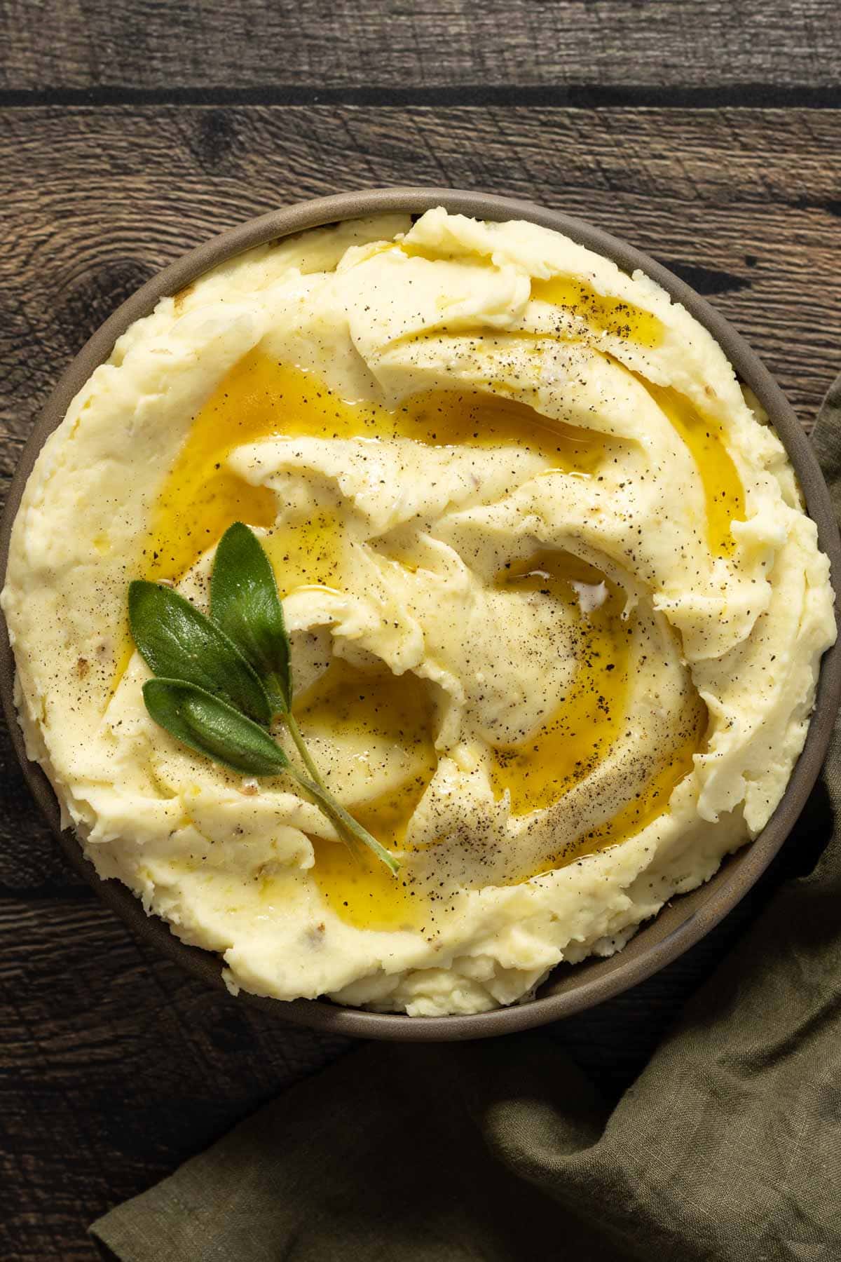 a bowl of mashed potatoes with sage and butter on top