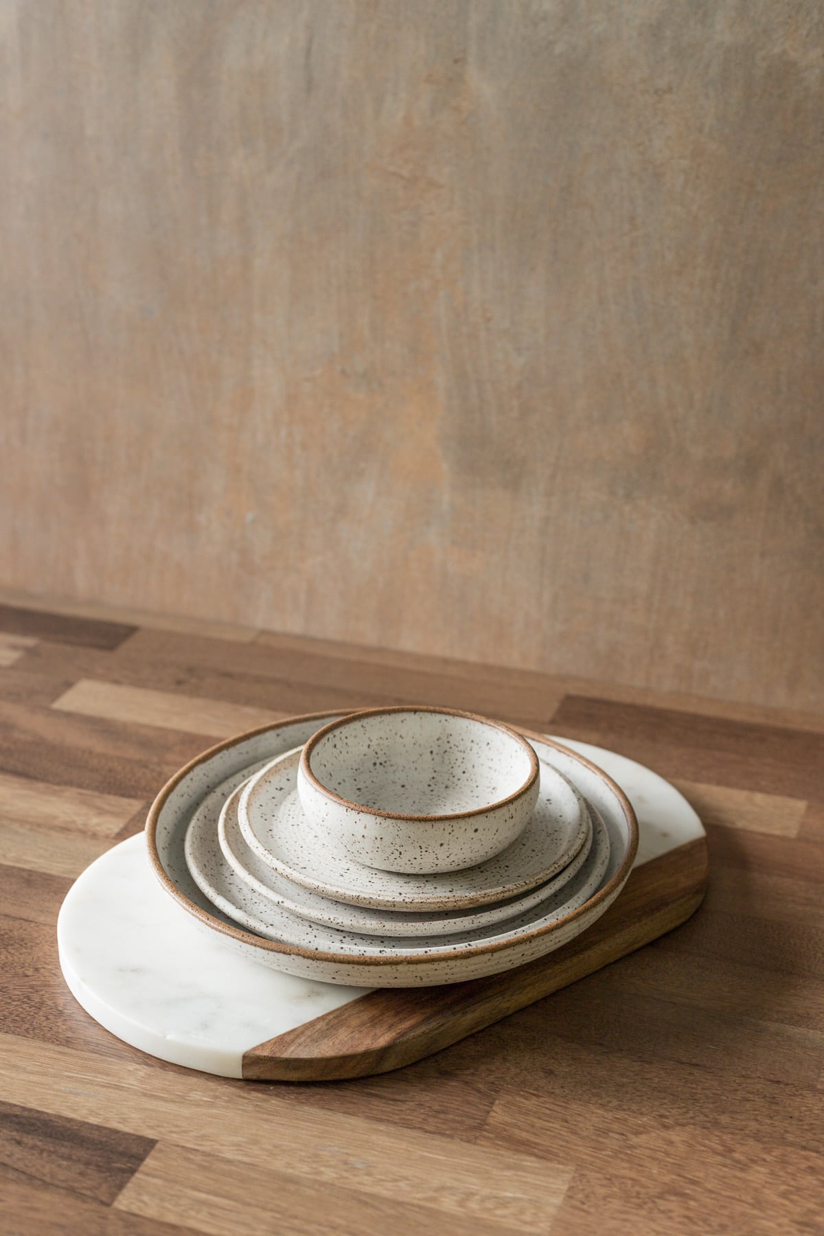 Pottery plate and bowls stacked on a marble cutting board