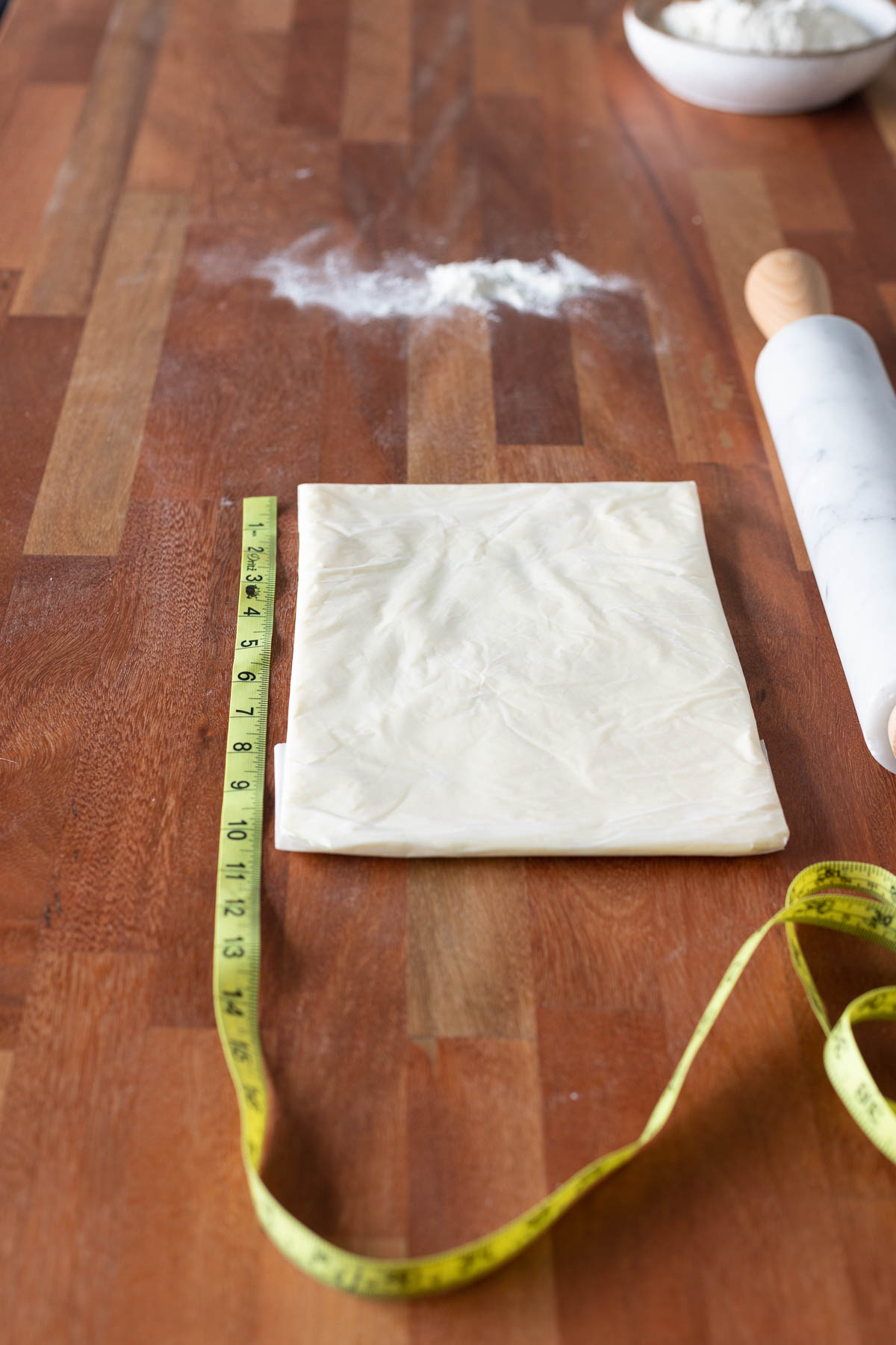 Butter rectangle rolled in parchment paper with a rolling pin