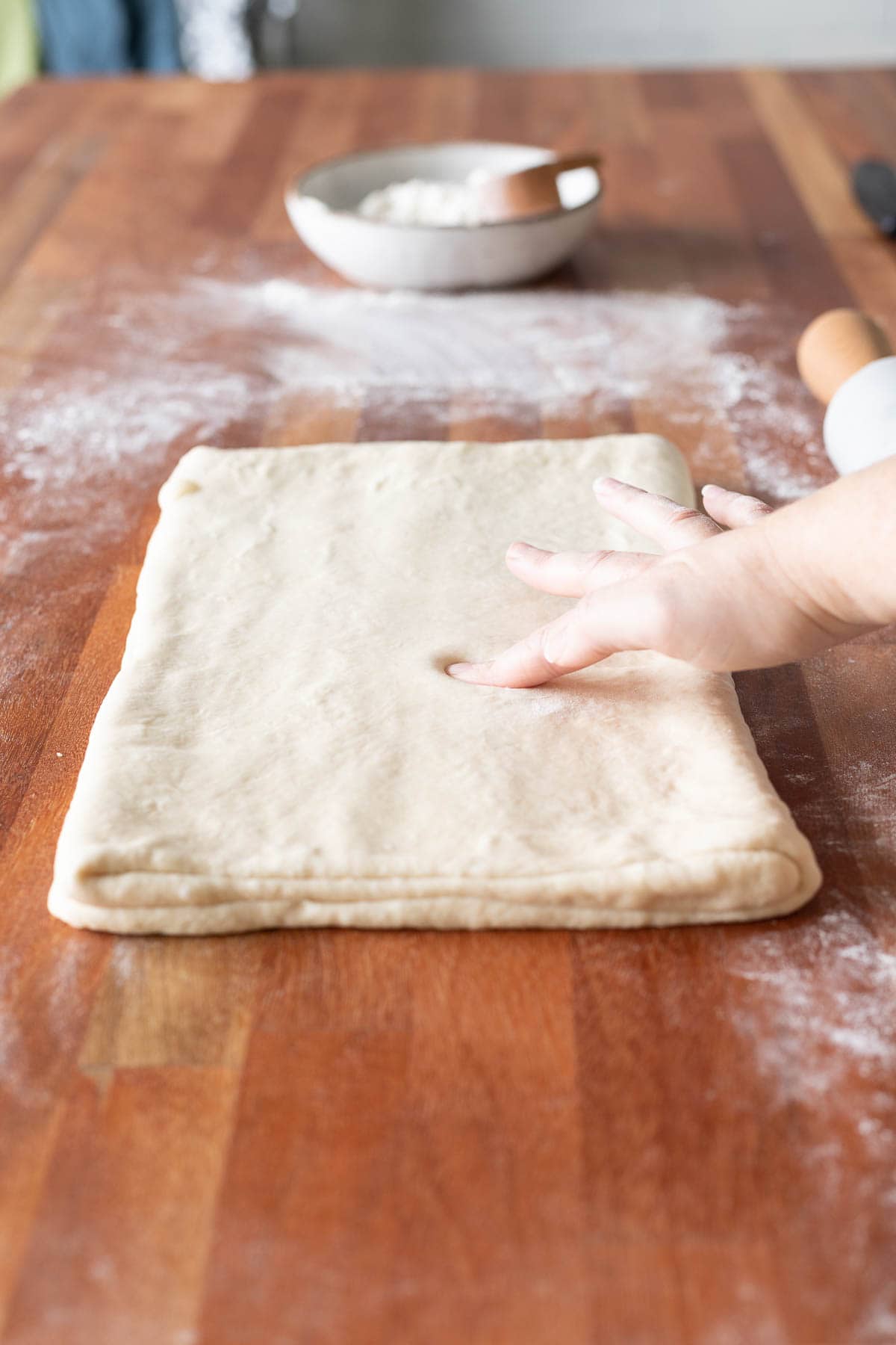 A hand putting a finger indention in croissant dough