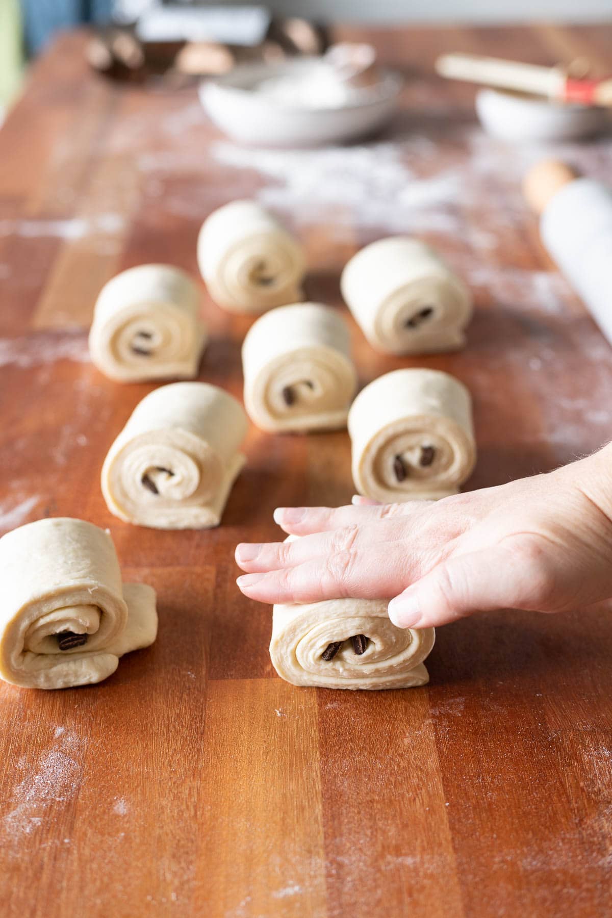 A hand pressing down chocolate croissants