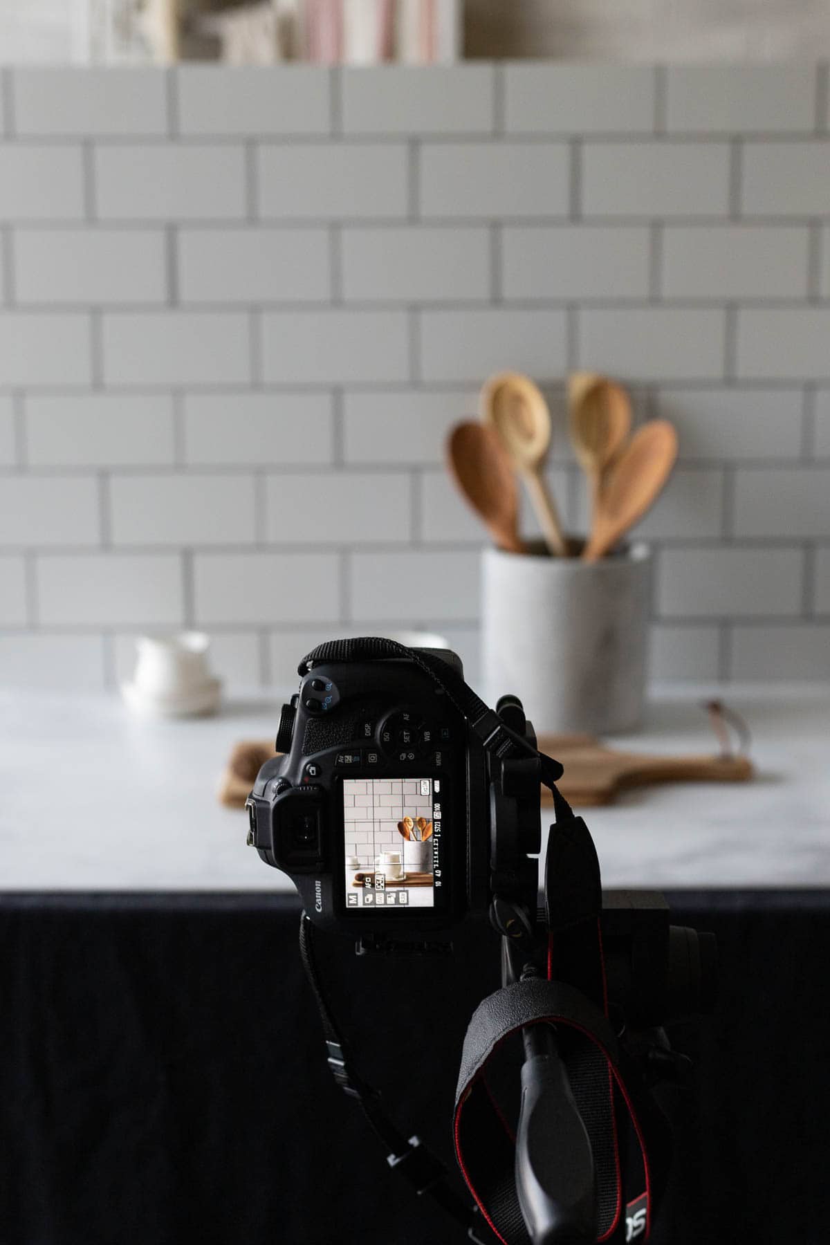 A camera taking a picture with a kitchen canister and subway tile backdrop