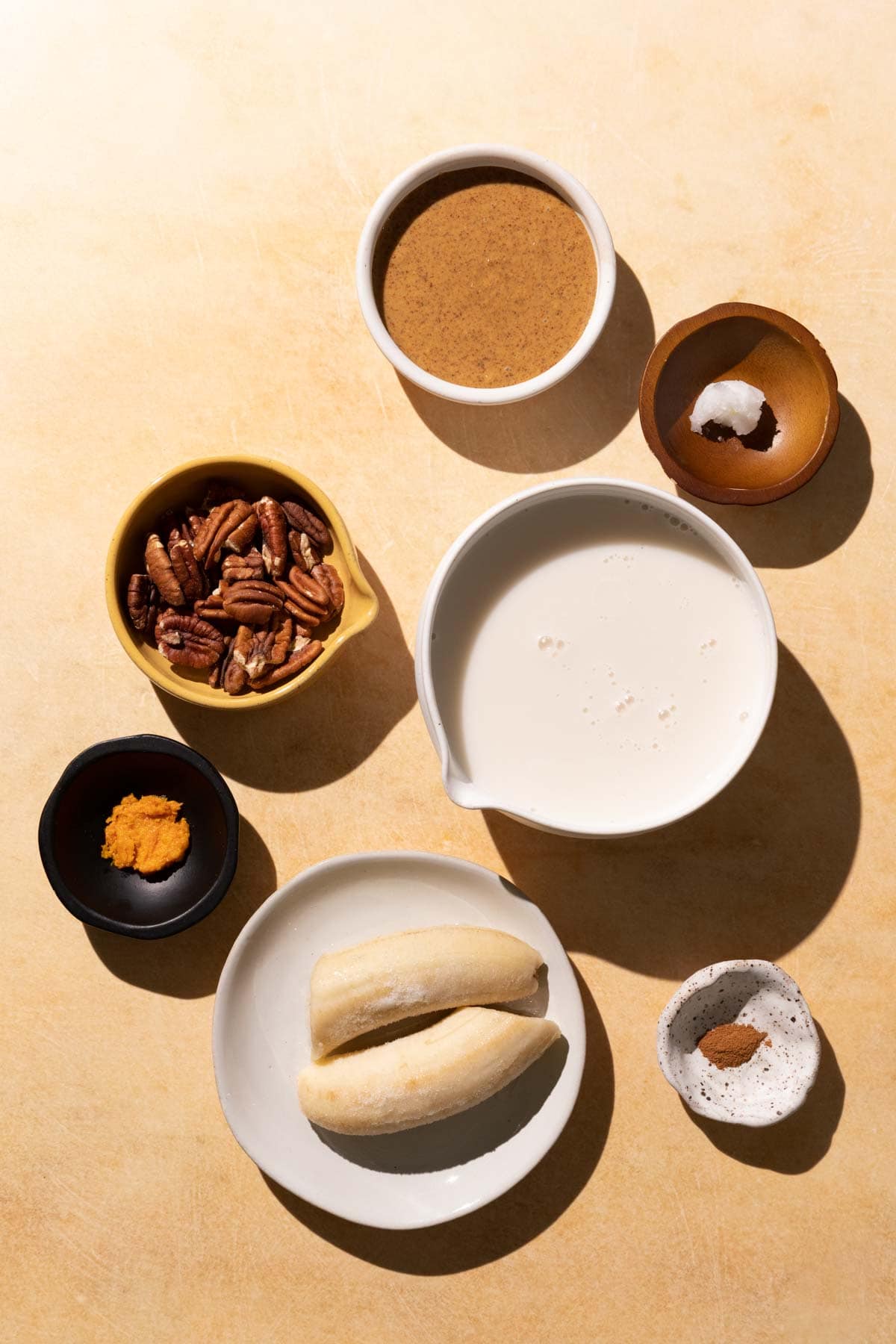 Ingredients for Banana Bread smoothie in bowls on a yellow background