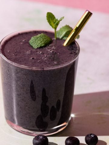 Blueberry Kale smoothie with mint and blueberries on a colorful background