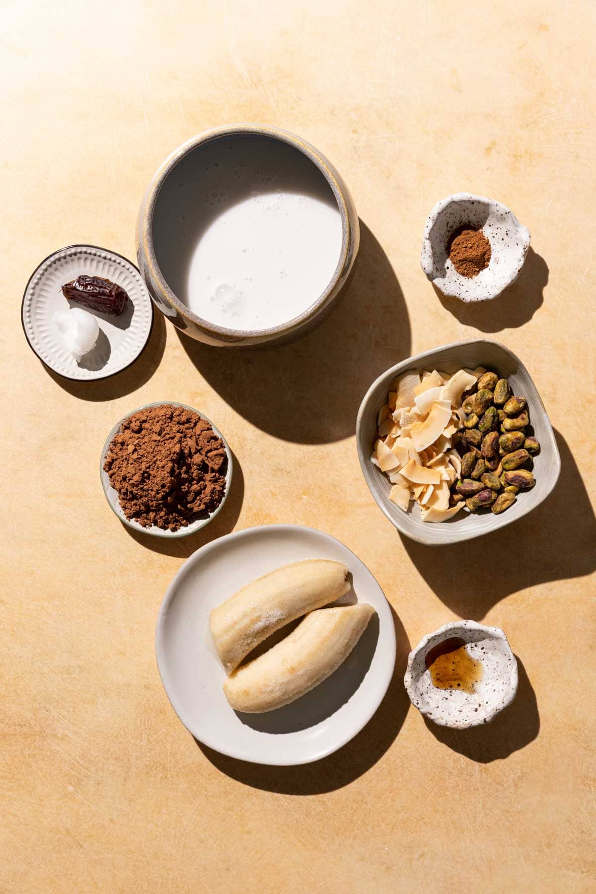 Ingredients for Chocolate Coconut smoothie in bowls on a yellow background