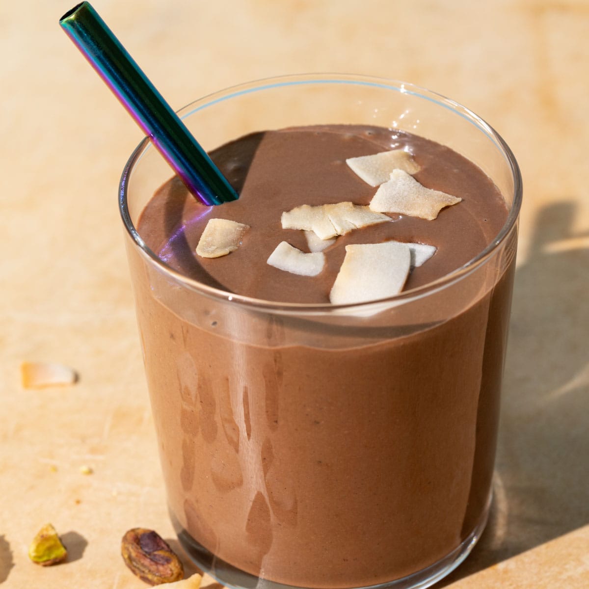 Close up of chocolate coconut smoothie with toasted coconut chips on a yellow background