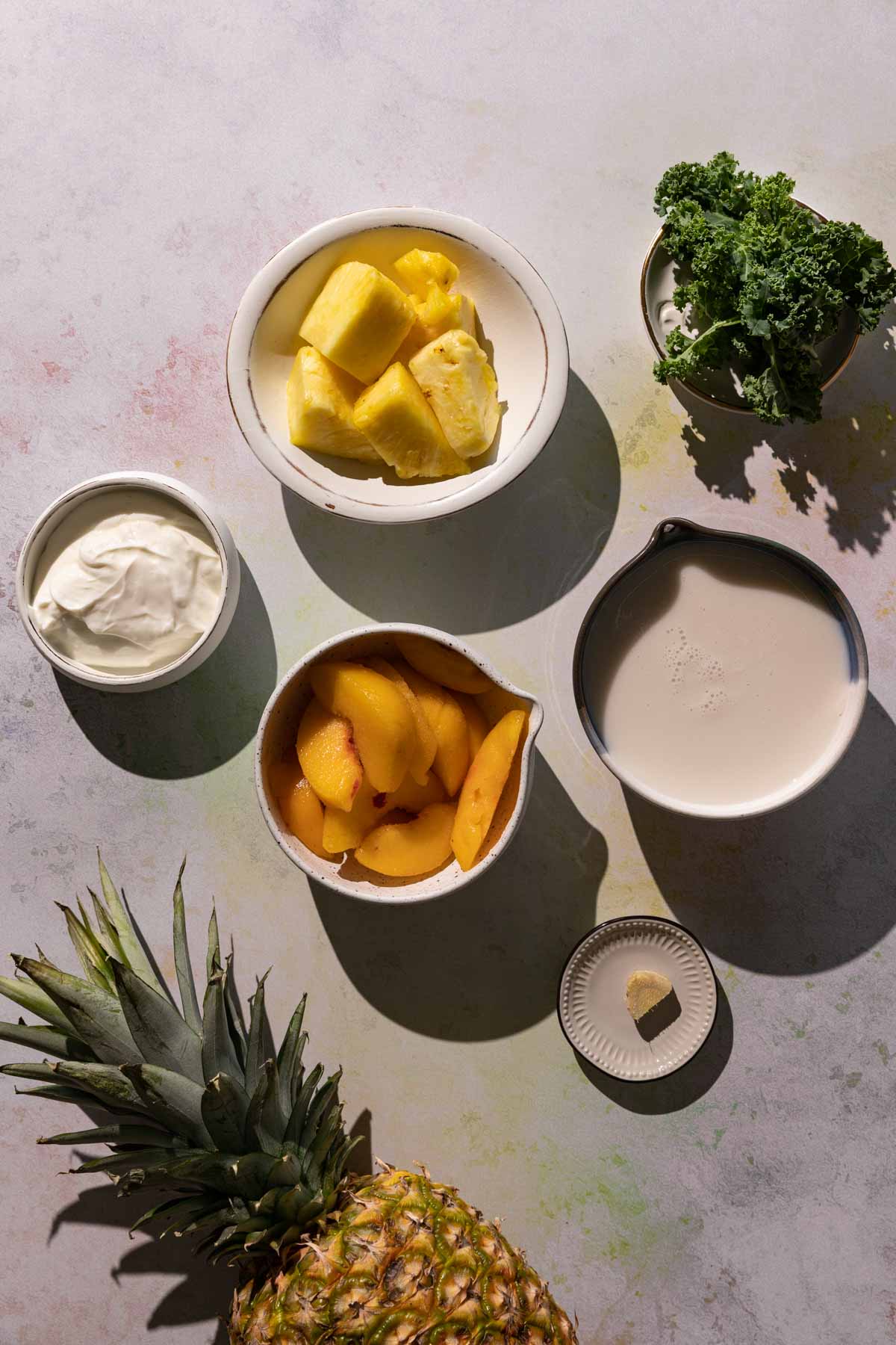 Ingredients for Pineapple Peach smoothie in bowls on a colorful background with whole pineapple