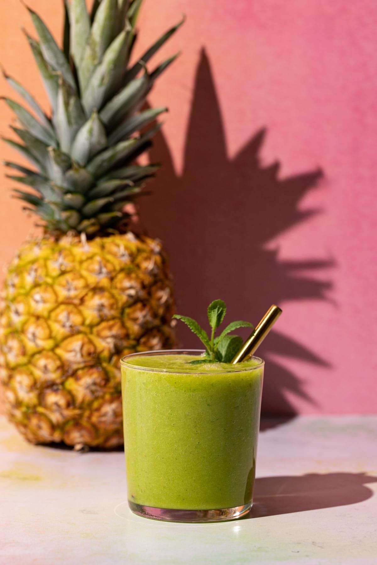 Mango Pineapple Kale smoothie on a colorful background with a pineapple