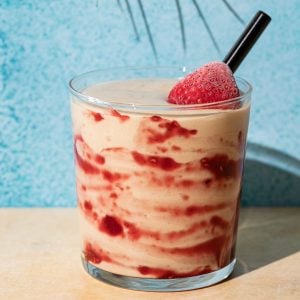 Close up of PB&J smoothie with strawberry and jelly swirl on a blue and yellow background