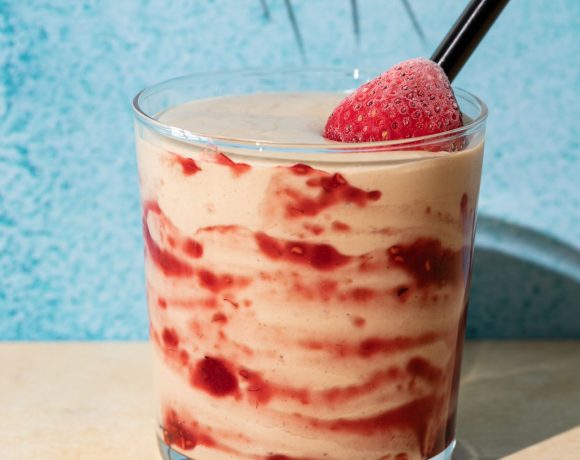 Close up of PB&J smoothie with strawberry and jelly swirl on a blue and yellow background