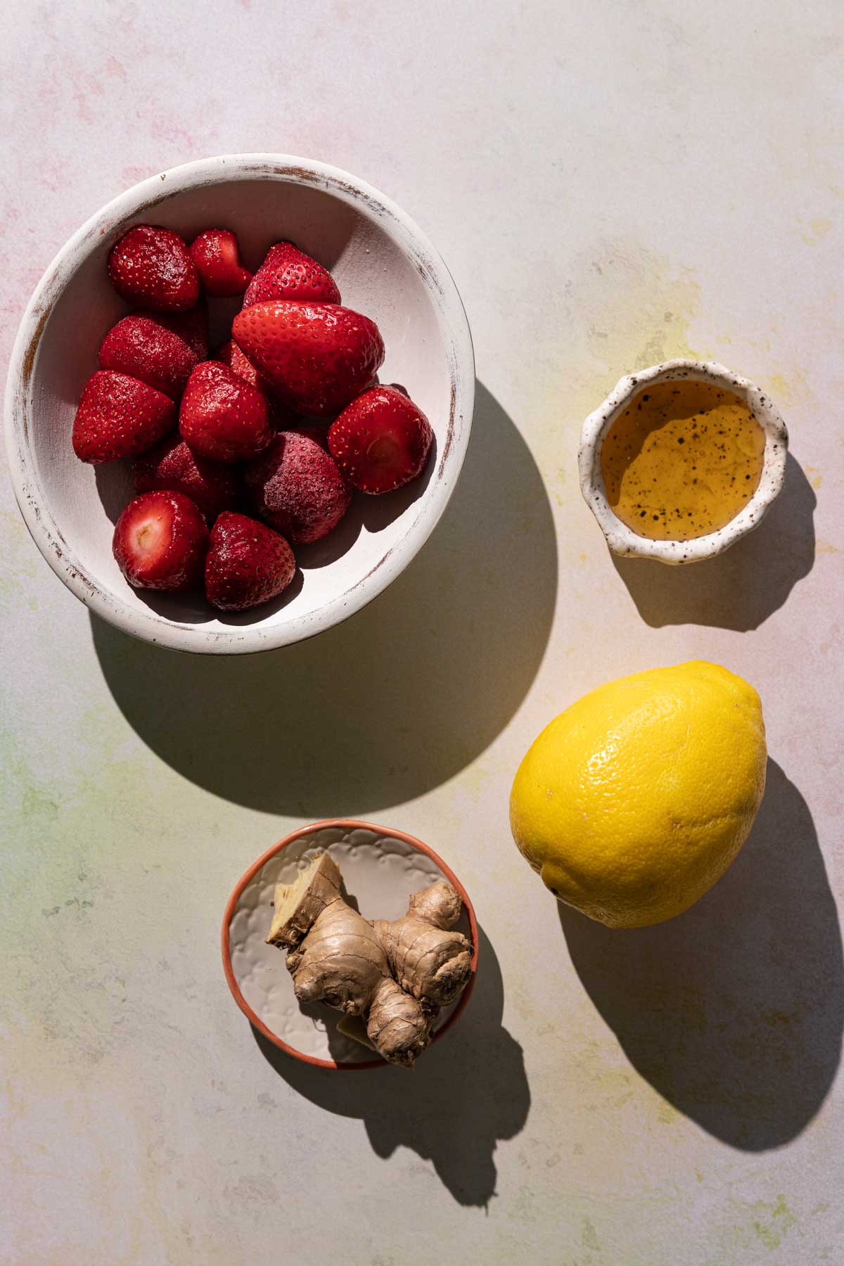 Ingredients for Strawberry Lemonade smoothie in bowls on a colorful background