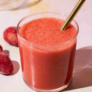 Close up of strawberry lemonade smoothie with a gold straw