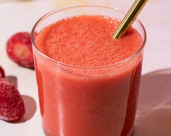 Close up of strawberry lemonade smoothie with a gold straw