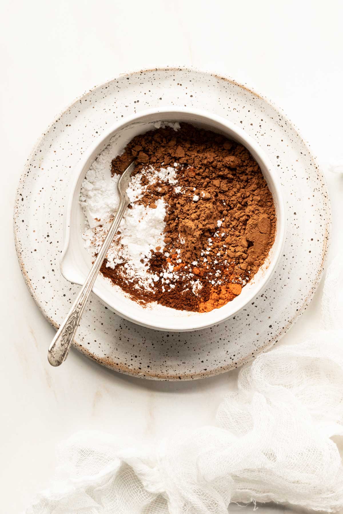 Cocoa powder and powdered sugar in a clay bowl with a spoon