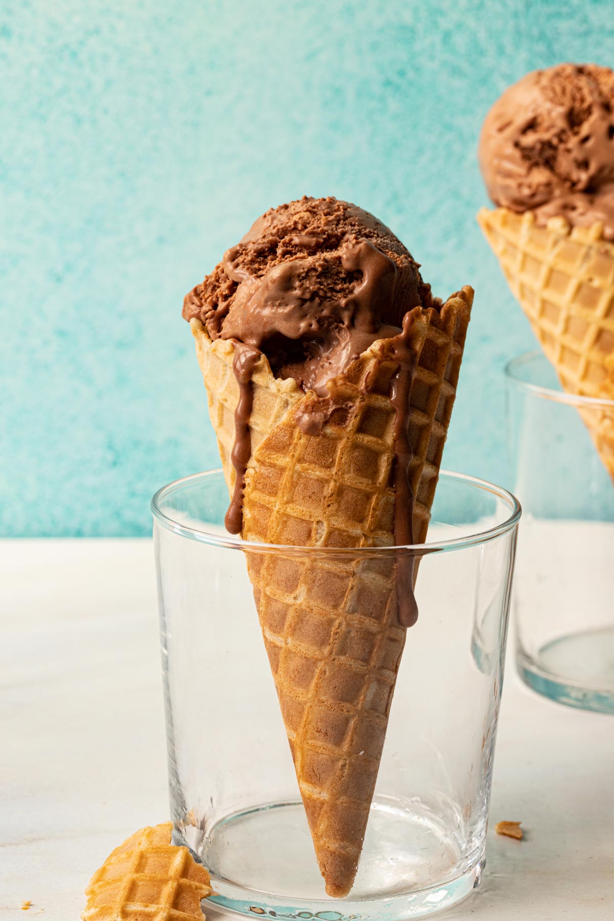 Two waffle cones in glasses with chocolate ice cream