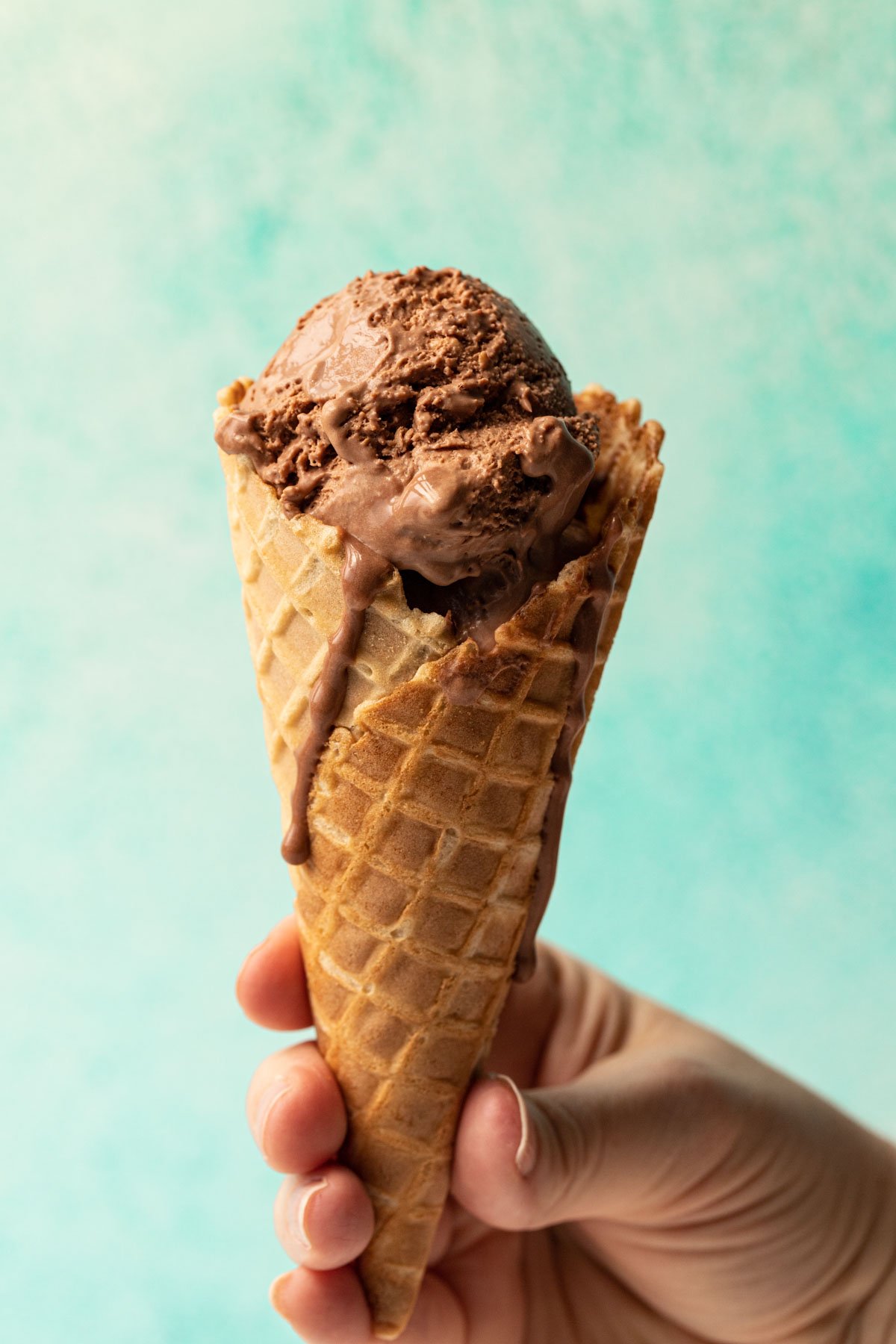 Chocolate no churn ice cream in a waffle cone held in a hand