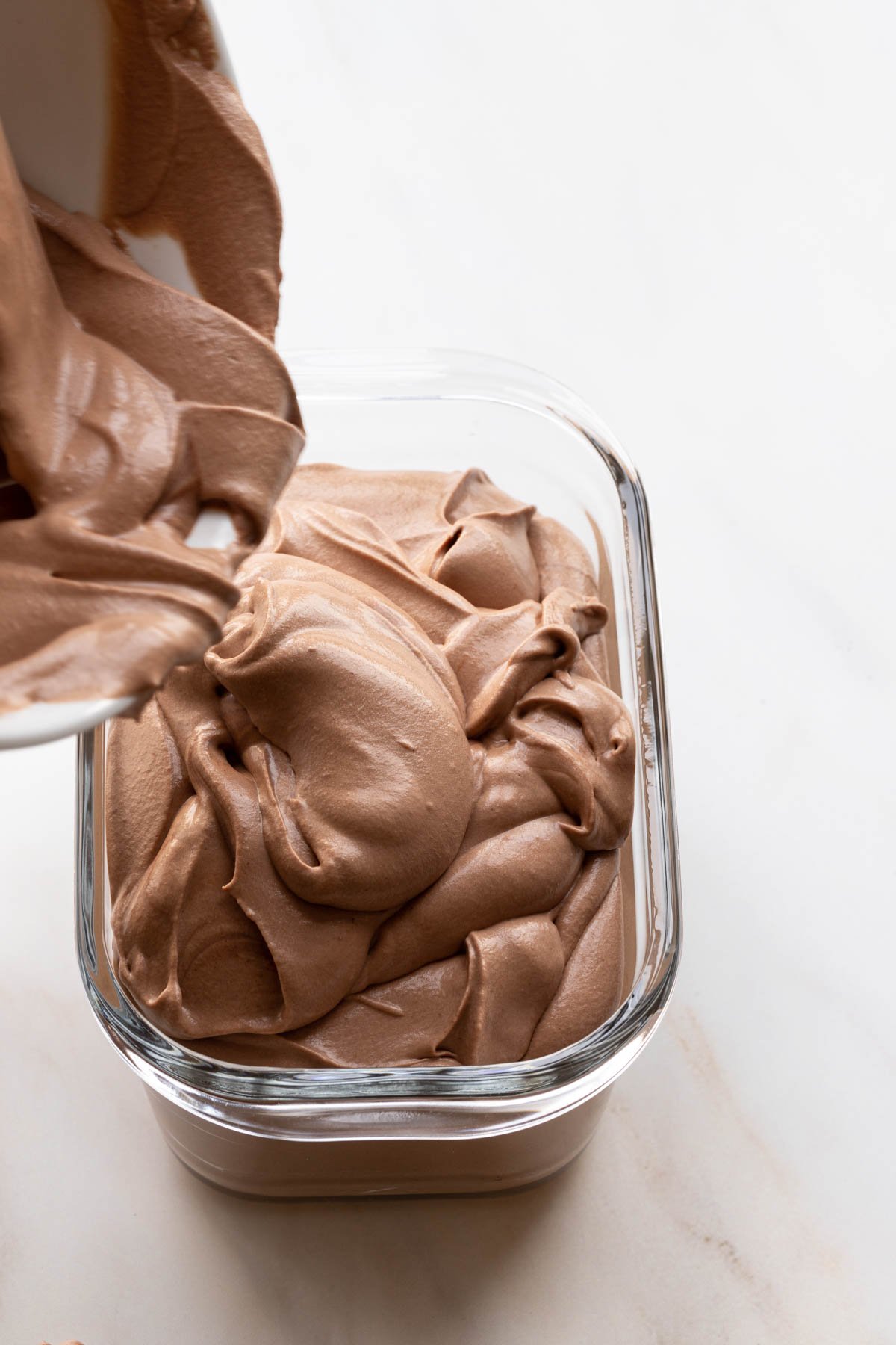 Pouring no churn chocolate ice cream into a glass container